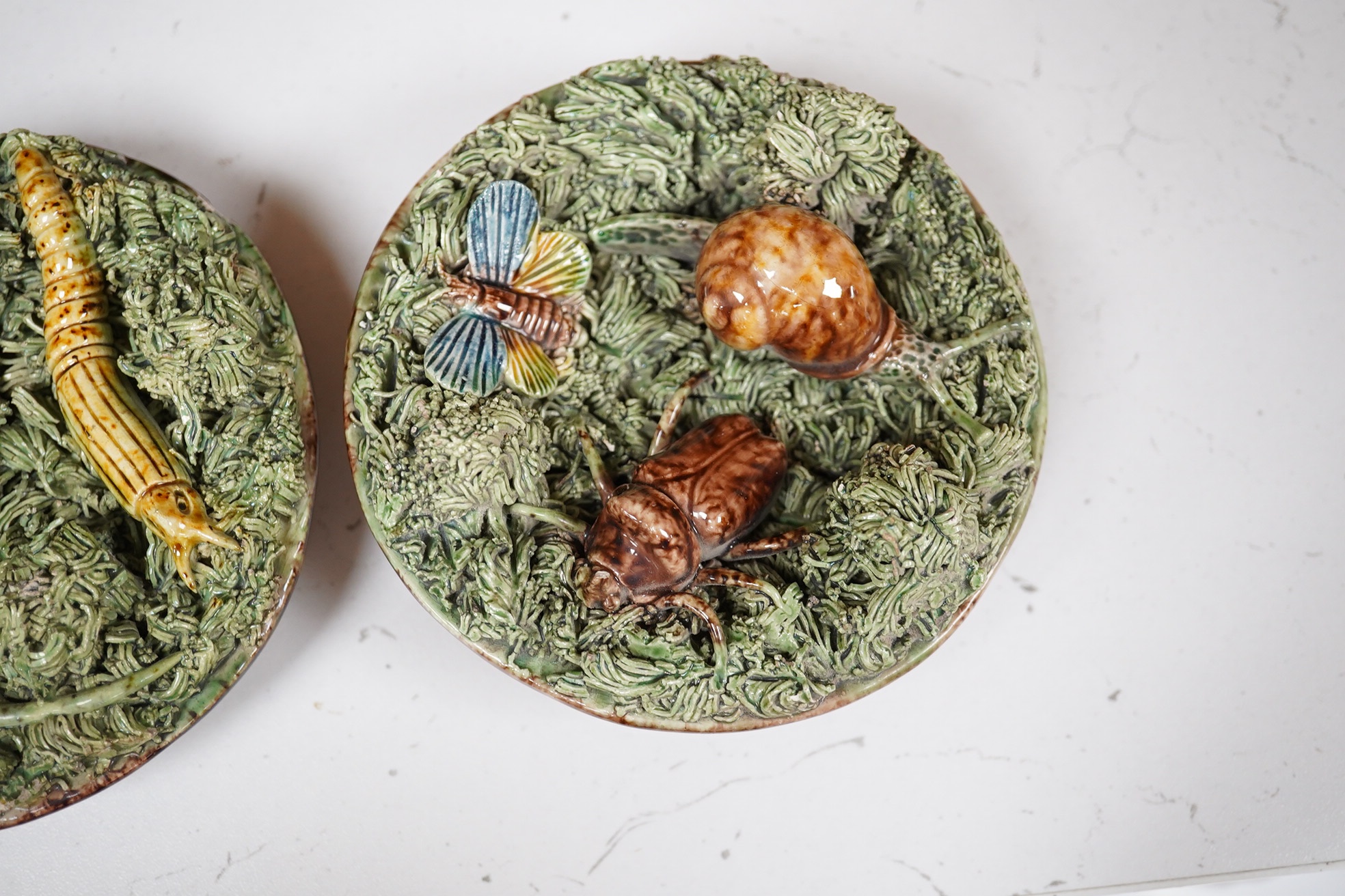 A pair of late 19th century Portuguese small circular Palissy style majolica plaques incorporating lizard and snail and with a mossy ground, impressed marks to reverse, 12cm diameter. Condition - fair